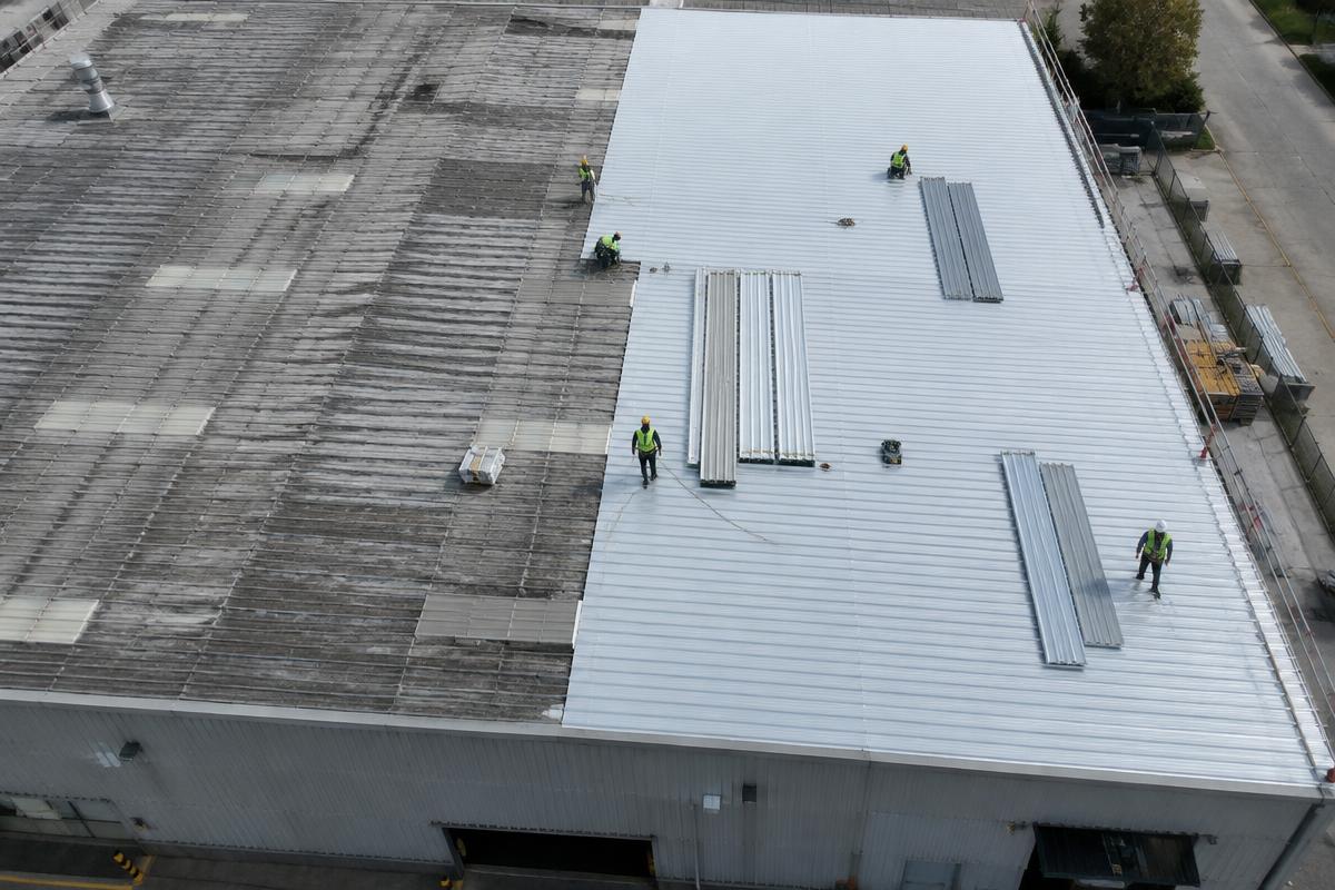 Vista aérea da troca de telhas metálicas no telhado de um galpão industrial